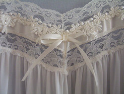 Lace appliqué and bow at the bust-line of a soft nylon nightgown.