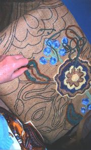 A craftsperson creates a hooked rug by pulling lengths of cloth, usually wool, through a woven fabric, usually burlap.